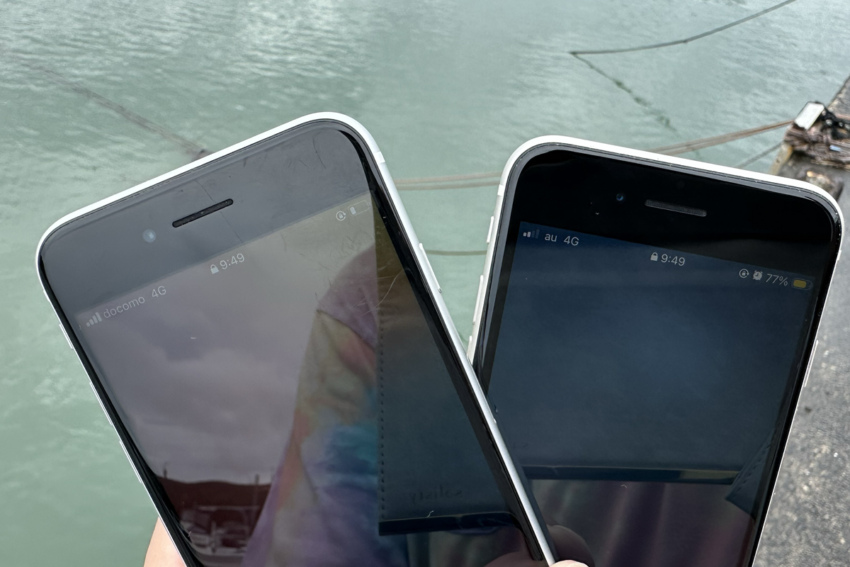 海辺でahamo(左・docomo 4G 4本)とpovo(右・au 4G 2本)のアンテナ本数を並べて撮影